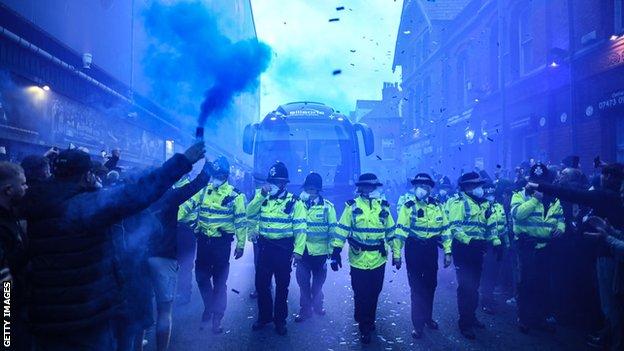 The Everton team coach is greeted by hundreds of supporters with blue flares being held