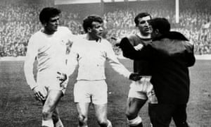 Leeds’ Billy Bremner (centre) is protected by teammate Norman Hunter as an angry home fan is held back by Everton’s Johnny Morrissey, 1964.