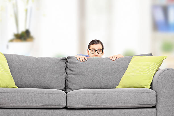 frightened-man-hiding-behind-a-sofa.jpg