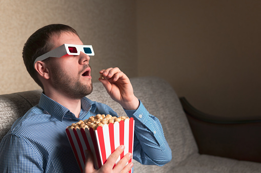 shocked-man-in-3d-glasses-eating-popcorn-at-home-picture-id1087587154