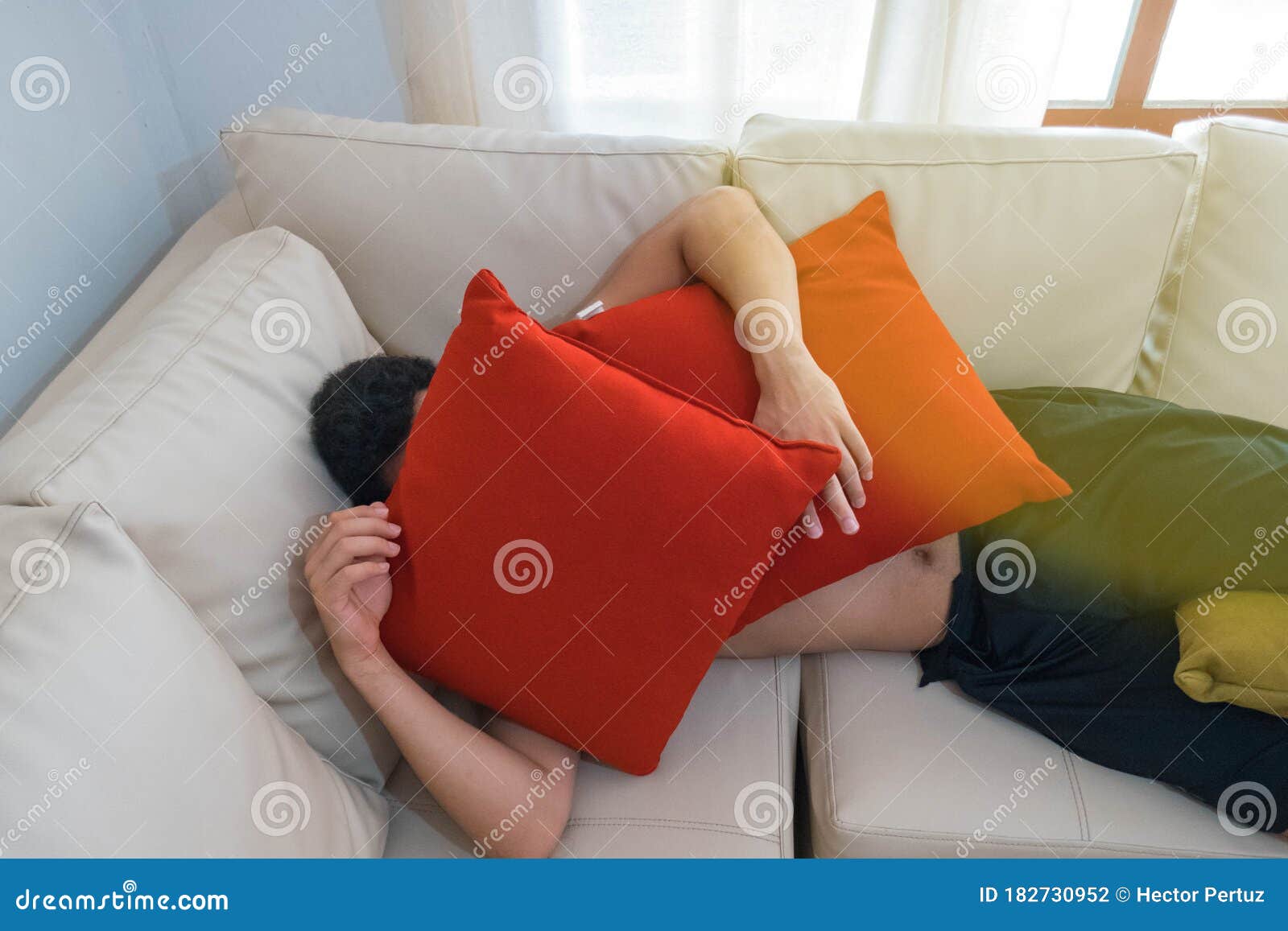 young-man-hiding-under-pillows-sofa-182730952.jpg